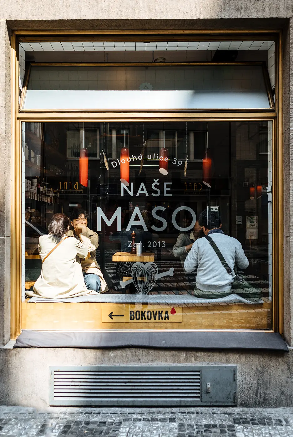 Naše maso butcher shop window on Dlouhá Street.